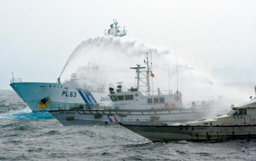 臺(tái)灣“海巡署”的巡邏船（中）在掩護(hù)保釣船“全家福”號（右）躲避日本海上保安廳巡視船的水炮攻擊。