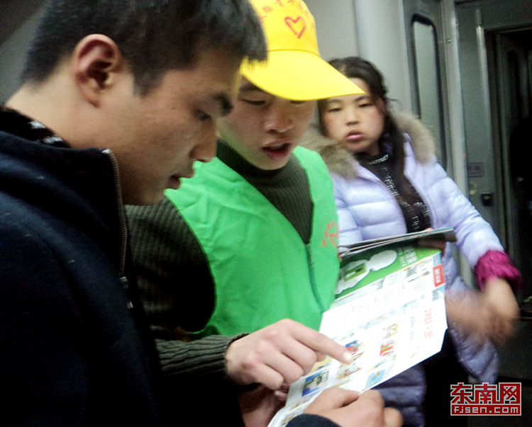 志愿者在列車(chē)上發(fā)放宣傳手冊(cè)(通訊員丁輝攝)